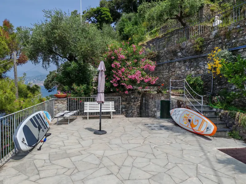 Sunny stone terrace with paddle boards, a parasol and flowering oleanders